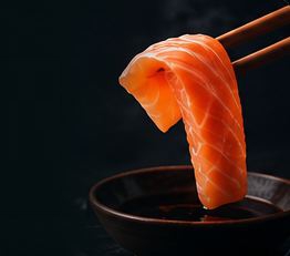 Sashimi held with chopsticks over soy sauce